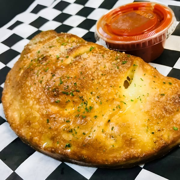 Golden-brown Sarappo's calzone with parmesan and parsley, served with a side of marinara sauce.